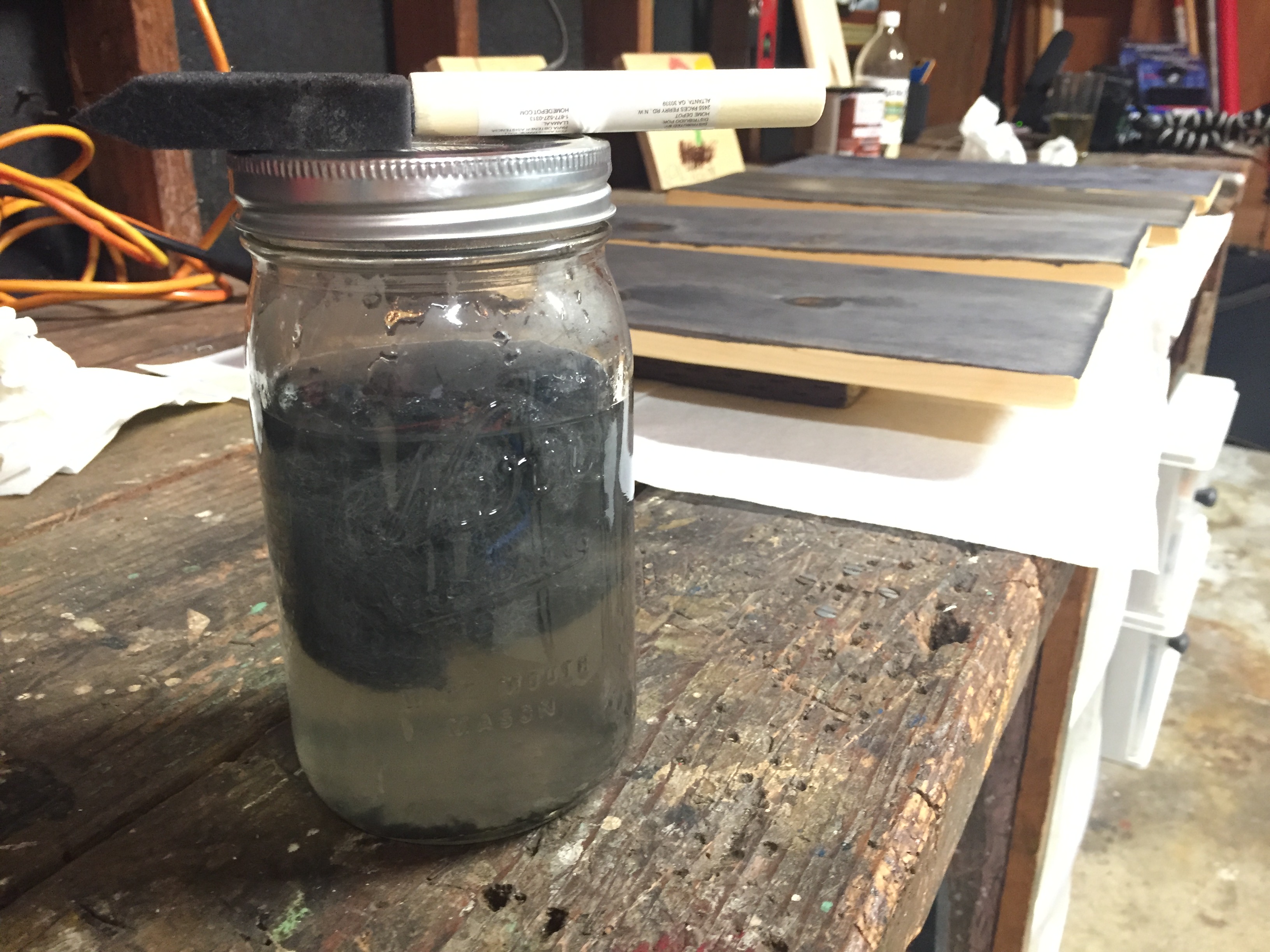 oxidation solution of steel wool and vinegar sitting on a workbench